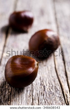 Ripe large chestnuts on a wooden surface. Selective focus.