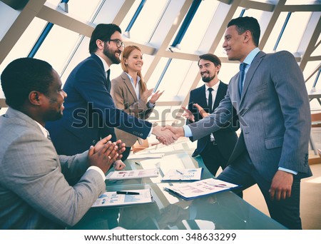 Business partners handshaking after signing contract Royalty-Free Stock Photo #348633299