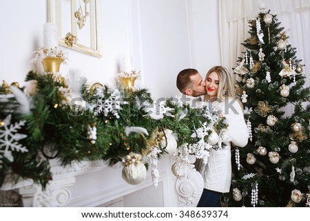 Young beautiful couple in the white room near a Christmas tree