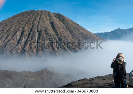 Woman taking a picture of the Mountain with fog and mist at volcano Bromo