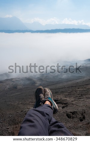 Feet with shoes in front of Sheet of Fog smoke or Mist at Volcano Bromo in Indonesia