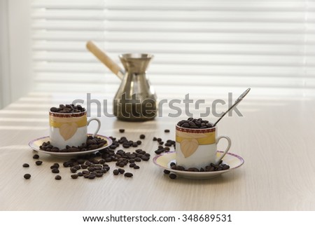 Coffee cups, coffee maker and coffee beans on the table.
