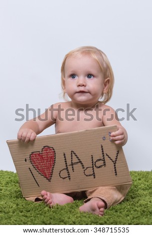 Small charming kid holding a sign "I love daddy!"
