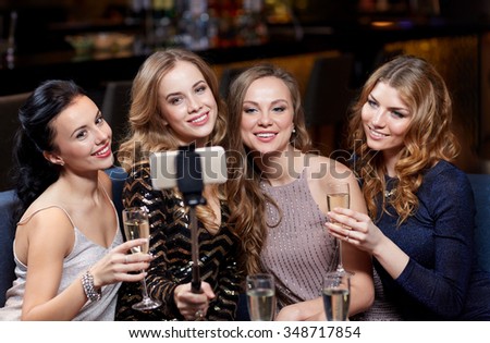 celebration, friends, bachelorette party, technology and holidays concept - happy women with champagne and smartphone selfie stick taking picture at night club