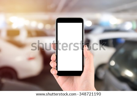 Smart phone with white screen in hand on Blur car parking background