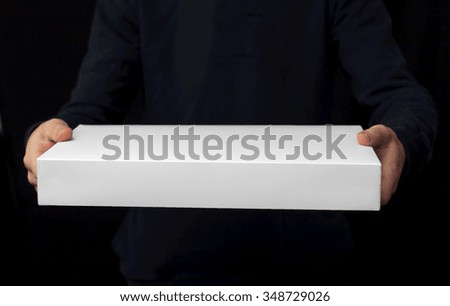 White box in man hands on black background