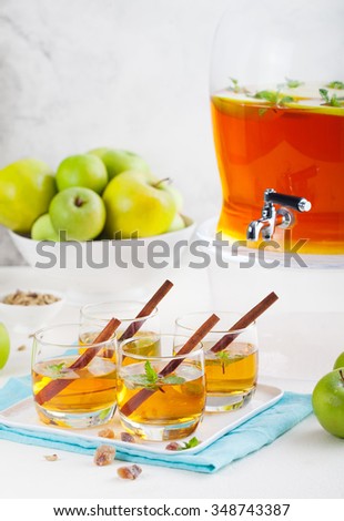 Apple, white wine punch, tea, mulled cider with spices in a beverage dispenser with fresh apples and mint leaves