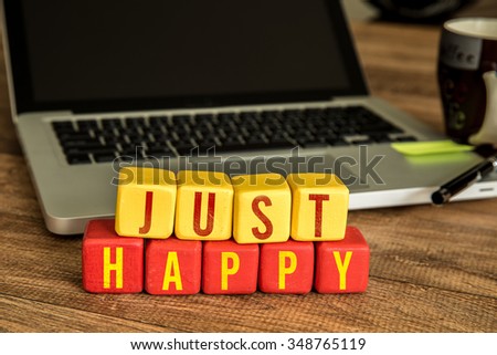 Just Happy written on a wooden cube in a office desk