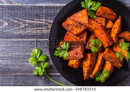 Homemade Cooked Sweet Potato with spices and herbs on dark background.