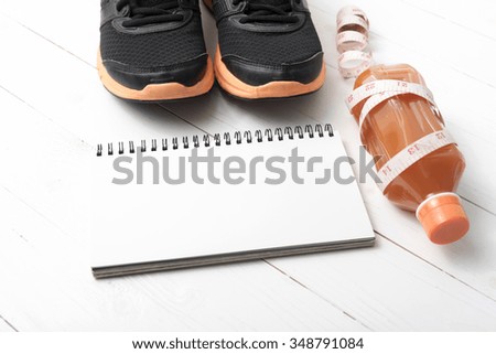 running shoes,orange juice,measuring tape and notepad on white wood background