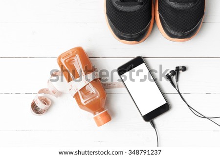 running shoes,orange juice,measuring tape and phone on white wood background