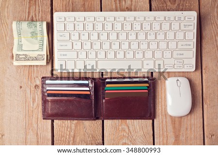 Online shopping concept with wallet, money and keyboard on wooden background. View from above