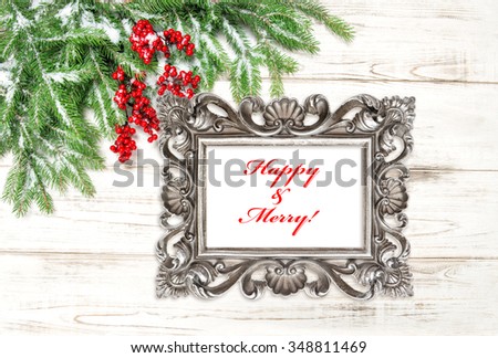 Christmas tree branches with red berries and snow. Vintage picture frame with sample text Happy & Merry!