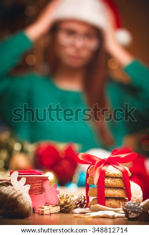Set of Christmas accessories on the table and a woman in a cap of Santa Claus in the background