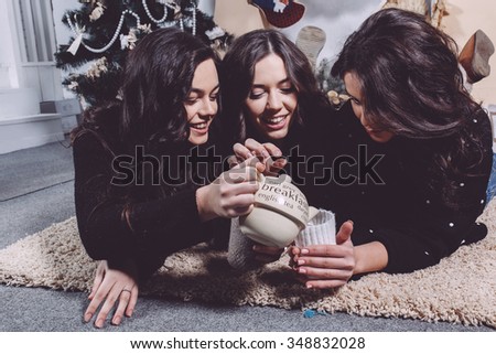 Beautiful girl eating Christmas cookies and drink tea while lying on a carpet. Decorative vintage apartment.