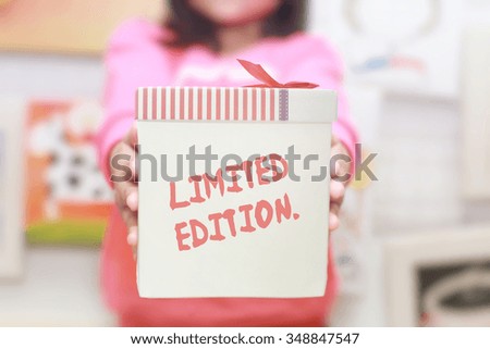 Gift box in young girl's hands with wording "LIMITED EDITION".Soft focus and very shallow depth of field composition.