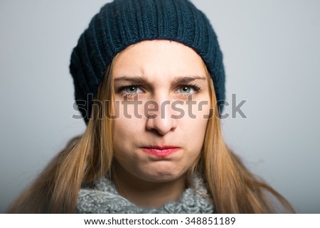 blonde girl offended, dressed in winter clothing, Christmas and New Year concept, studio photo isolated on a gray background