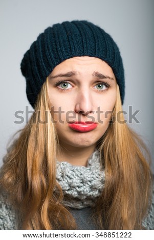 blonde girl offended, dressed in winter clothing, Christmas and New Year concept, studio photo isolated on a gray background