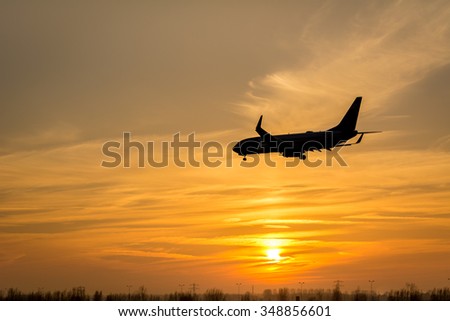 Airplane is flying towards the runway from the airport. Photo taken during a beautiful sunset.