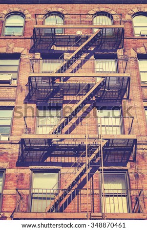 Vintage style photo of New York building with fire escape ladders, USA.