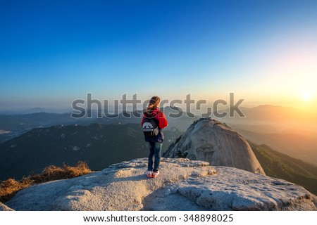 Woman stands on the peak of stone in Bukhansan national park,Seoul in South Korea and watching to Sunrise. Beautiful moment the miracle of nature. Royalty-Free Stock Photo #348898025
