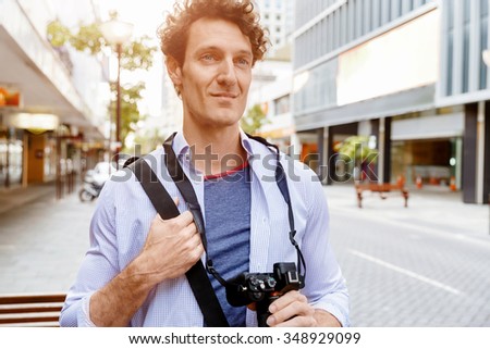 Happy male tourist walking in city with camera
