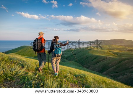 Young couple hike in the mountains. A man and a woman walking and looking at the beautiful landscape. Royalty-Free Stock Photo #348960803