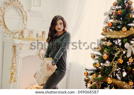 Young stylish girl with Christmas gifts and New Year decoration. Soft warm color tone.