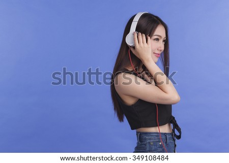 Young woman with headphone listening music on blue background