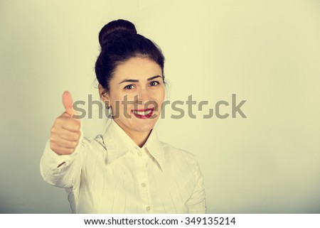 Success business woman excited giving thumbs up.Success woman showing thumbs up.Excited beautiful woman isolated on grey background.