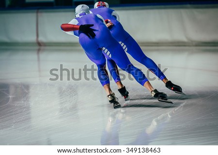 young men athletes skater equally roll during warm-up before competitions in speed skating