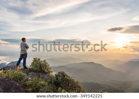 Young happy tourist on top of a mountain enjoying valley view Royalty-Free Stock Photo #349142225