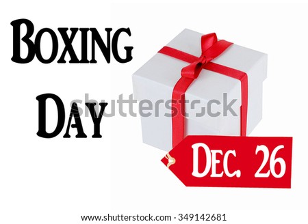A simple white square box tied with a bright red ribbon with a red sales tab isolated on white.  Boxing Day is on December 26th each year, a day of great sales and commercial activity. Text added.