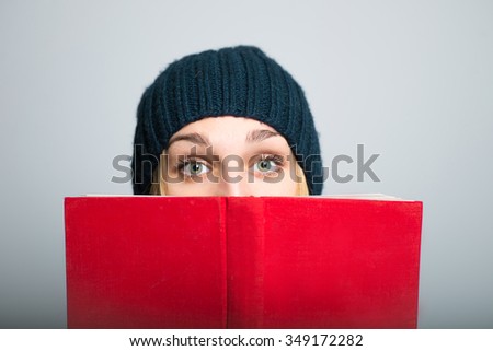 blonde girl hiding behind the book, Christmas and New Year concept, studio photo isolated on a gray background