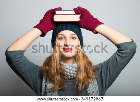 blonde girl with books on the head, Christmas and New Year concept, studio photo isolated on a gray background