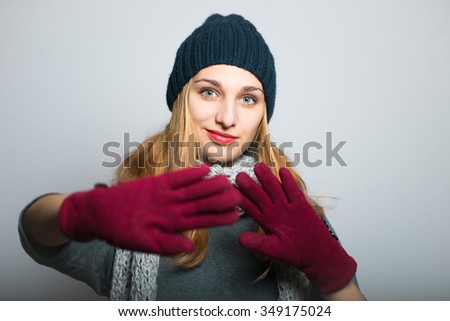 blonde girl shows stop in winter clothes, Christmas and New Year concept, studio photo isolated on a gray background