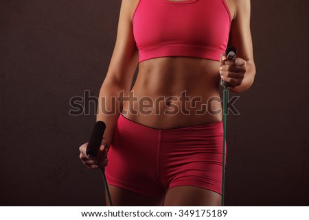 Sport, activity. Cute woman with skipping rope. Muscular girl black background.