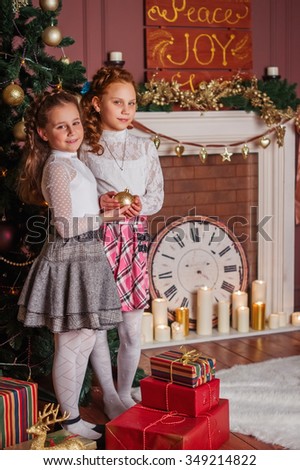 Christmas photo: two girls sisters near Christmas tree