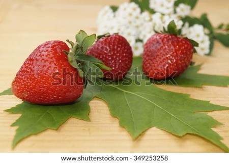 Strawberries and leaves on wooden black background 