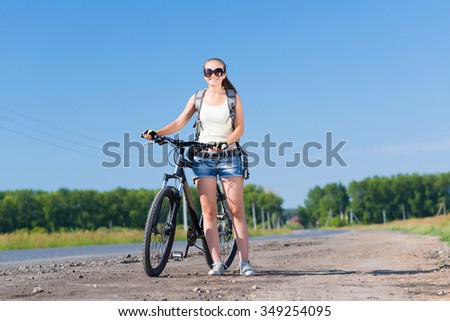 Young pretty woman with backpack walking with bicycle outdoors
