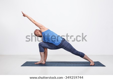 Young fit woman doing Ashtanga Vinyasa Yoga asana Utthita parsvakonasana - extended side angle pose advanced variation Royalty-Free Stock Photo #349259744