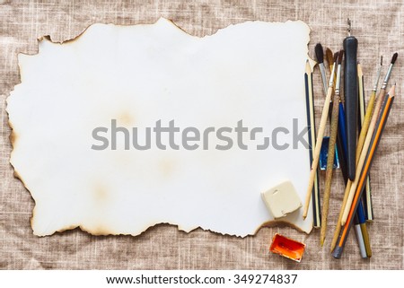 vintage rustic mockup: old burn paper, paints for drawing, pencils and brushes on a linen cloth background