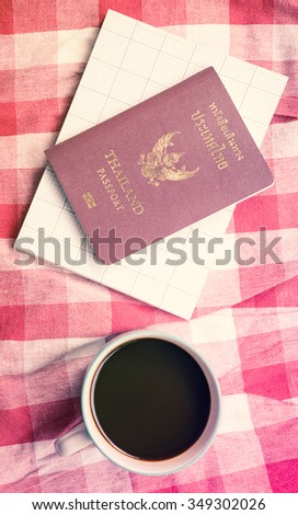 top view Coffee cup and passport book on plaid fabric