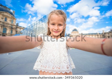 Adorable little girl taking selfie with mobile phone outdoors in Paris