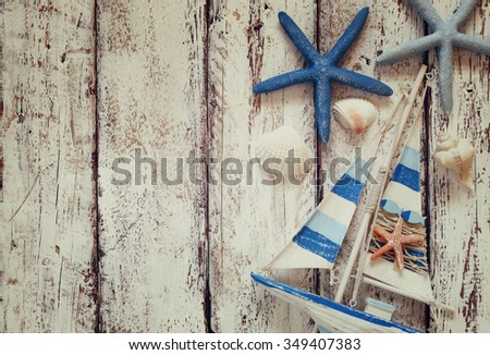 top view image of wood boat, sea shells and star fish over wooden table. retro filtered