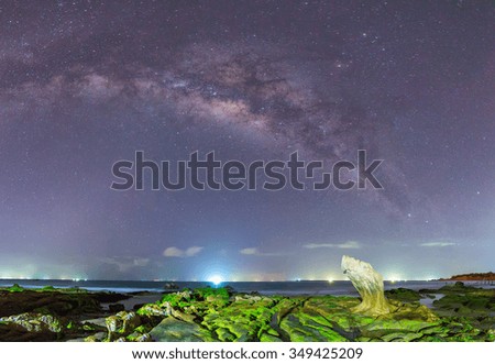 Milky Way ancient moss fossil inside the reef at night with bright constellation formed long colorful streaks, below the moss-covered rocks on the beach while enjoying beautiful galaxy in the night