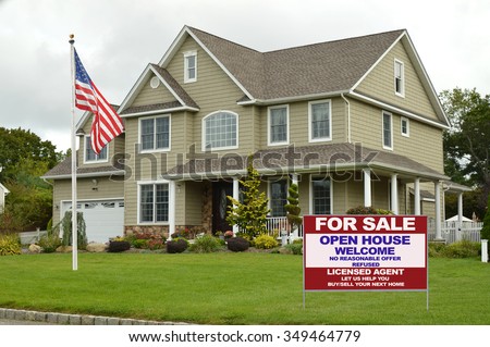American flag pole Real estate for sale open house welcome sign Suburban McMansion style home overcast cloudy day residential neighborhood USA