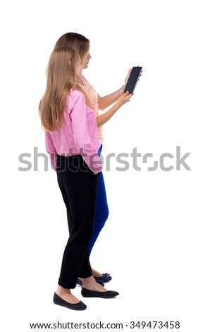 Back view of two young woman look at smart phone. Rear view people collection.  backside view person. Rear view. Isolated over white. Two girls blonde stand cancer looking at tablet computer