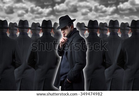 Mysterious man making a silence gesture while standing out from the crowd Royalty-Free Stock Photo #349474982