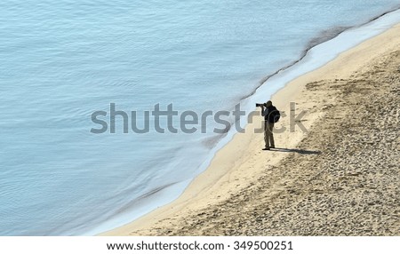 One single photographer taking pictures near the sea, photographer at work
